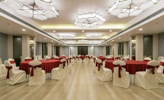 a large conference room with rows of tables and chairs , all covered in red tablecloths at Regenta Central Jaipur