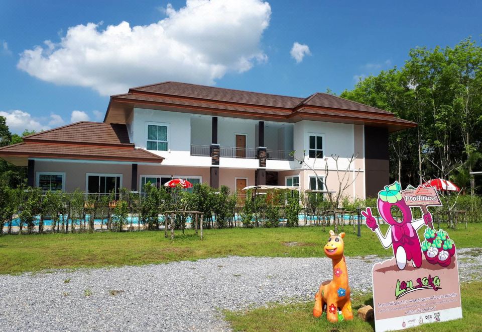 a large house surrounded by a grassy yard , with a giraffe statue in the front yard at Pool House Lanska