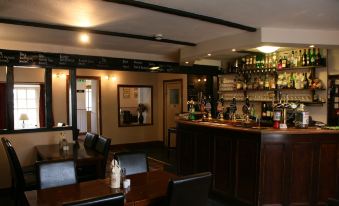 a bar with a wooden counter and chairs , along with a dining table and chairs at Red Lion Inn