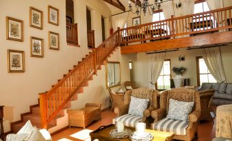 a spacious living room with a wooden staircase , multiple couches , and a coffee table in the center at Hole in One