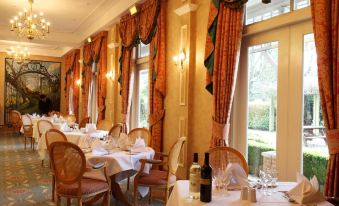 a dining room with a large window and a row of chairs set up for a meal at Coulsdon Manor Hotel and Golf Club