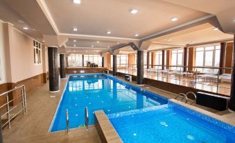 an indoor swimming pool with a blue water surface and surrounding facilities , including wooden flooring and glass windows at Well Hotel