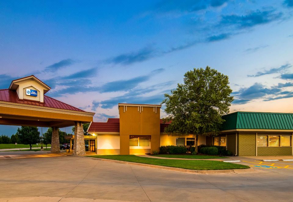 a large building with a red roof and a green roof is lit up at night at Best Western Wichita North