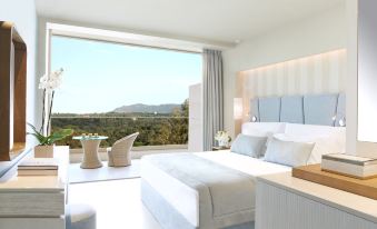 a luxurious bedroom with a large bed , white linens , and a view of the mountains outside the window at Ikos Dassia