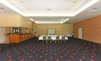 a large conference room with a black and white patterned carpet , tables , chairs , and a counter at Windmill Motel and Events Centre