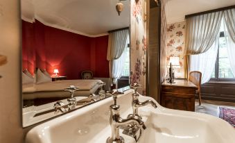 a bathroom with a sink , toilet , and bathtub , as well as a bedroom with a bed at Grandhotel Giessbach