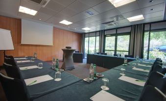 a conference room set up for a meeting , with multiple chairs arranged in rows and a projector on the wall at Hôtel du Golf