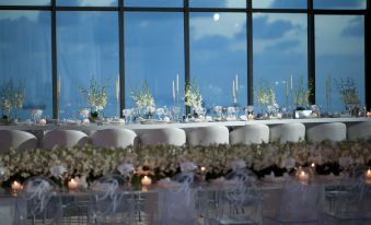 a long dining table set up for a wedding reception , with white tablecloths and chairs arranged in rows at Le Royal Hotel - Beirut