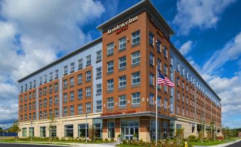 a brick building with a large sign on the side and an american flag in front at Residence Inn Boston Needham