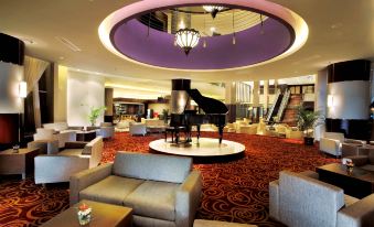 a large hotel lobby with a grand piano in the center , surrounded by couches and chairs at ASTON Purwokerto Hotel & Convention Center