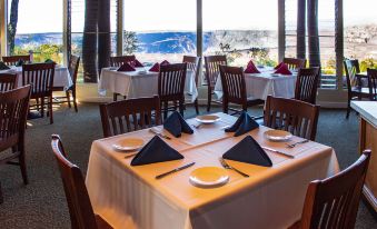 a restaurant with multiple tables set for dining , each table having a white tablecloth and blue napkins at Volcano House