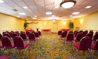 a large conference room with rows of red chairs and a table set up for an event at Buffalo Airport Hotel