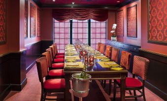 a long dining table with red chairs and yellow place settings is set up in a room with red walls at Westminster Hotel