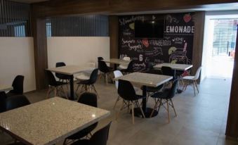 a dining area with several tables and chairs , some of which are occupied by people at Hangar Inn Guadalajara Aeropuerto