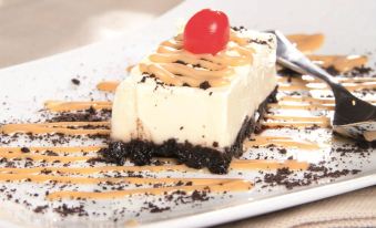 a slice of cake with a cherry on top , drizzled with caramel sauce and sprinkled with blacksesame seeds , is presented on a plate at Hotel Union