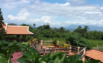 a wooden deck with a view of the mountains and clouds , surrounded by lush greenery at Tara Lodge Haven of Peace