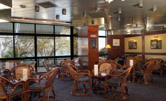 a room with wooden chairs and tables , a large window , and a christmas tree in the background at Hotel Estoril Eden