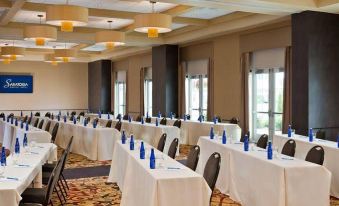 a large conference room with multiple tables set up for a meeting , each table has a blue bottle on it at Saratoga Casino Hotel