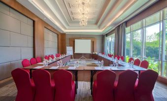 a conference room with red chairs arranged in a semicircle around a table , and a projector on the wall at Ramada Suites by Wyndham Solo