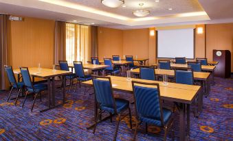 a conference room with blue chairs and tables , a screen on the wall , and large windows at Courtyard Richmond Northwest/Short Pump