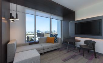 a modern living room with a large window , a couch , and a tv . the room has hardwood floors , a coffee table ,. at Aloft Perth