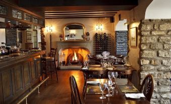 a restaurant with wooden tables and chairs , a fireplace , and wine glasses on the table at The Horseshoe Country Inn