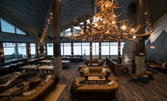 a large , dimly lit room with multiple couches and chairs arranged around a dining table at Mountain Lodge