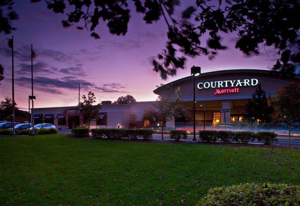 a large building with a courtyard marriott sign in front of it , surrounded by trees at Courtyard Montvale