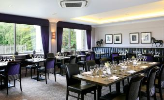 a well - decorated dining room with multiple tables and chairs arranged for a group of people at Macdonald Berystede Hotel and Spa