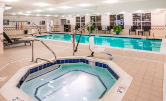 an indoor swimming pool with a hot tub , surrounded by lounge chairs and tables , in a well - lit indoor space at Residence Inn Waynesboro