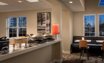a modern kitchen with a dining area featuring a table and chairs , as well as a large window that allows natural light to enter at Residence Inn West Springfield