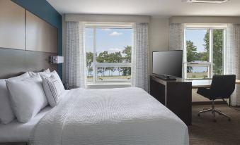 a bedroom with a large bed , desk , and tv , overlooking a lake through a window at Residence Inn Boston Bridgewater