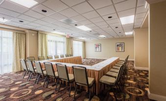 a large conference room with multiple tables and chairs , surrounded by framed art on the walls at Hilton Garden Inn Meridian
