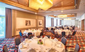 a large dining room filled with round tables and chairs , ready for guests to enjoy a meal at Leonardo Hotel Karlsruhe