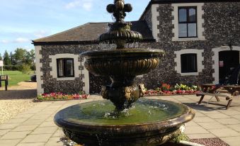 a water fountain in front of a stone building , surrounded by a well and greenery at Coach House Hotel