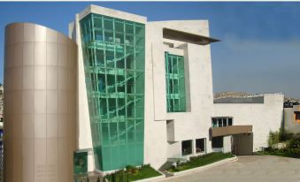 a modern building with a green glass facade and white walls , situated in front of a clear sky at Hotel Madeira