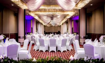 a large banquet hall is set up with white chairs and tables , ready for an event at Radisson Blu Hotel, Szczecin