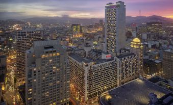 a cityscape at dusk , with a large building in the foreground and several other buildings in the background at Hilton San Francisco Union Square