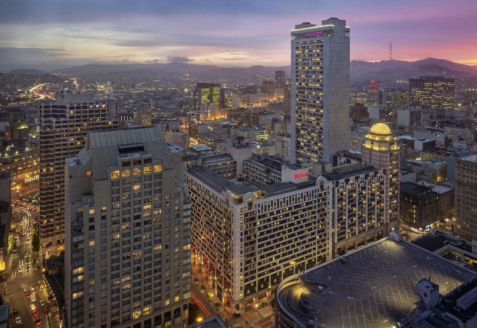 a city skyline at dusk , with tall buildings lit up and a dome in the center at Hilton San Francisco Union Square