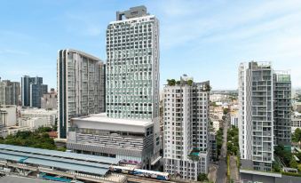 From an aerial perspective, multiple towering buildings are visible, with one positioned prominently in the foreground, adjacent to the ocean at Avani Sukhumvit Bangkok Hotel