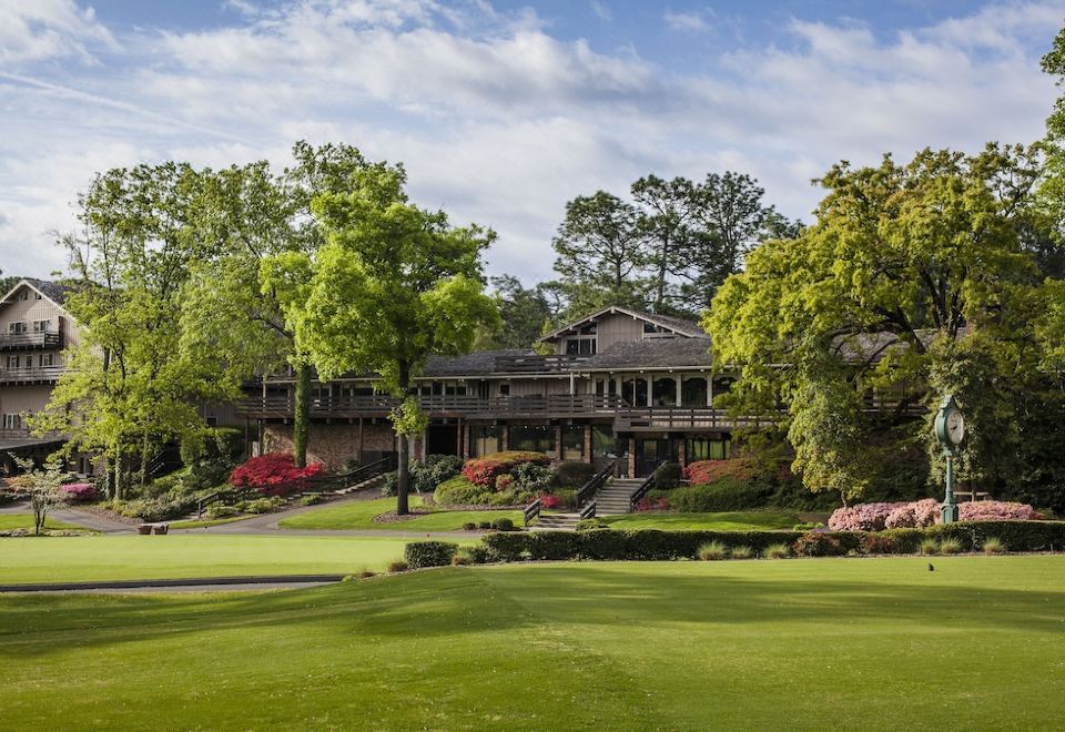 a large house is surrounded by trees and flowers , with a green lawn in front of it at Pine Needles Lodge & Golf Club