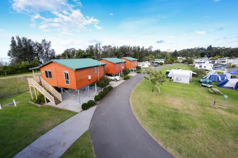 an aerial view of a residential area with multiple orange houses and green roofs , surrounded by trees and grass at Discovery Parks - Eden