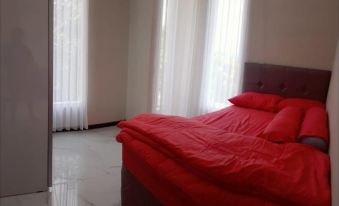 a red bed with a pillow and blanket , situated in a room with white walls and large windows at Villa Orlando