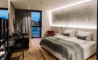 a modern hotel room with a large bed , wooden flooring , and a balcony view of the city at Hotel A