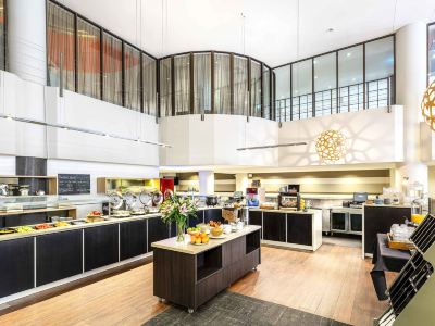 a large dining area with a buffet table and various food items on display , such as fruits and desserts at Ibis Melbourne Hotel and Apartments