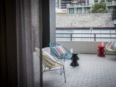 a balcony with two chairs and a small table , overlooking a cityscape from a high - rise apartment at Ibis Melbourne Hotel and Apartments