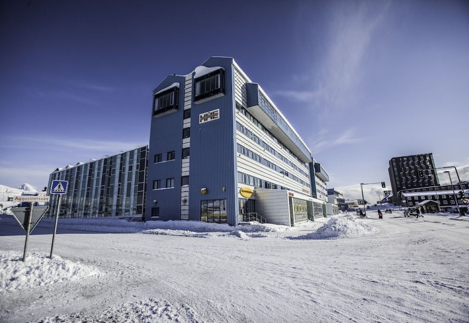 "a large building with a blue facade is surrounded by snow and has a sign reading "" gravelville ""." at Hotel Hans Egede