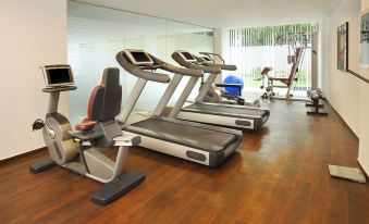 a gym with treadmills and exercise bikes in a room with wooden floors and large windows at Four Points by Sheraton Ahmedabad