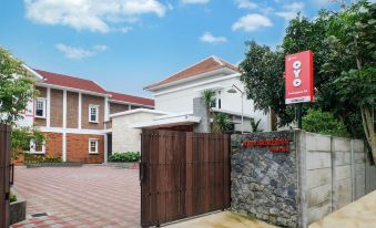 a gate with a red sign and a stone wall in front of a red brick building at Super OYO Collection O 2383 Andongkoe 64 Salatiga