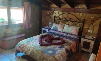 a cozy bedroom with a bed covered in a colorful blanket and a teddy bear on the bed at La Esencia